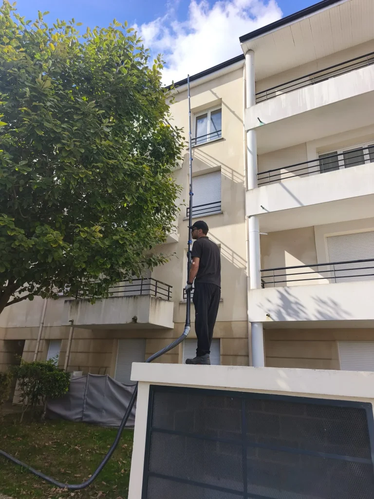 Technicien nettoyant la façade d un immeuble à la perche télescopique